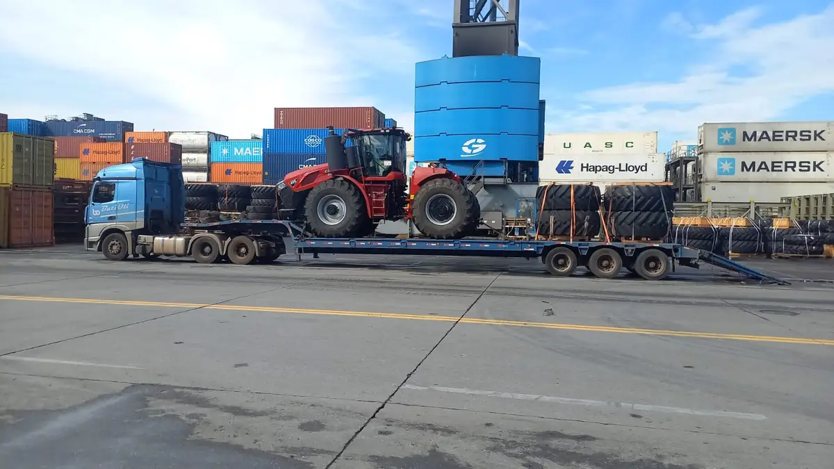 Trator articulado embarcado em prancha em área portuária